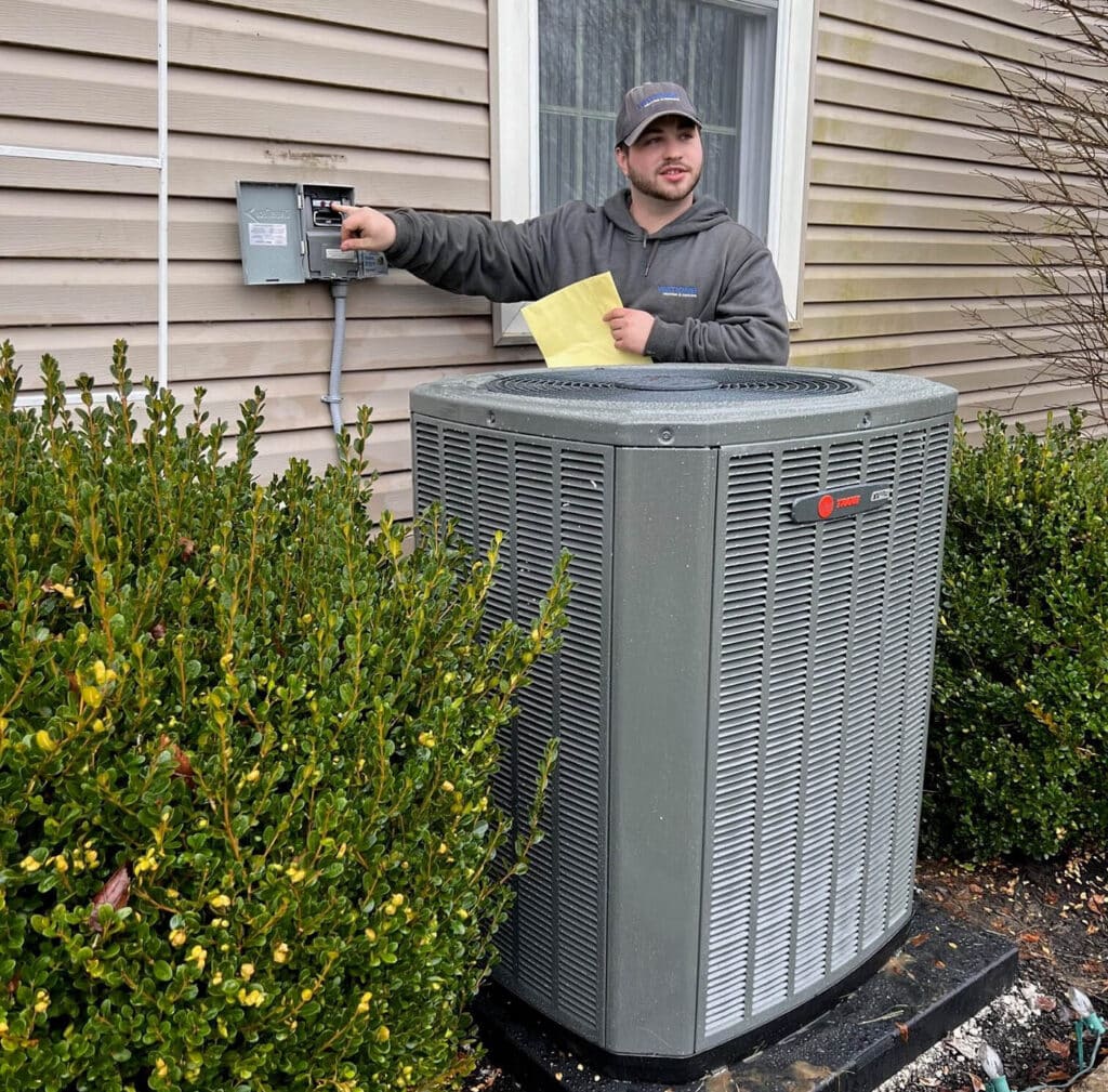 Watkins HVAC tech explains new installed Trane air conditioning unit to customer outside